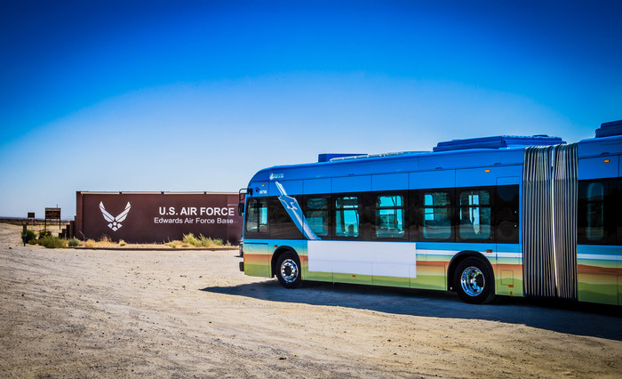 AVTA Bus parked outside of the entrance to Edwards Air Force base next to the sign.