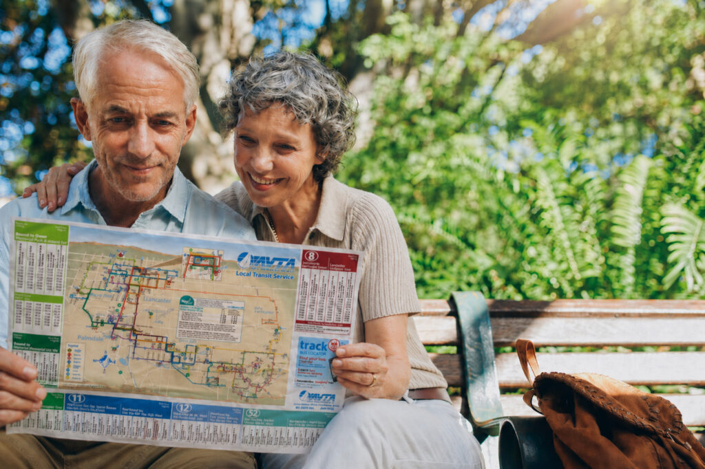 Elderly couple browsing the AVTA schedule together on a park bench.