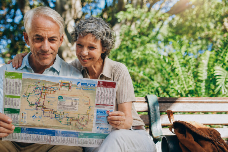 Elderly couple browsing the AVTA schedule together on a park bench.