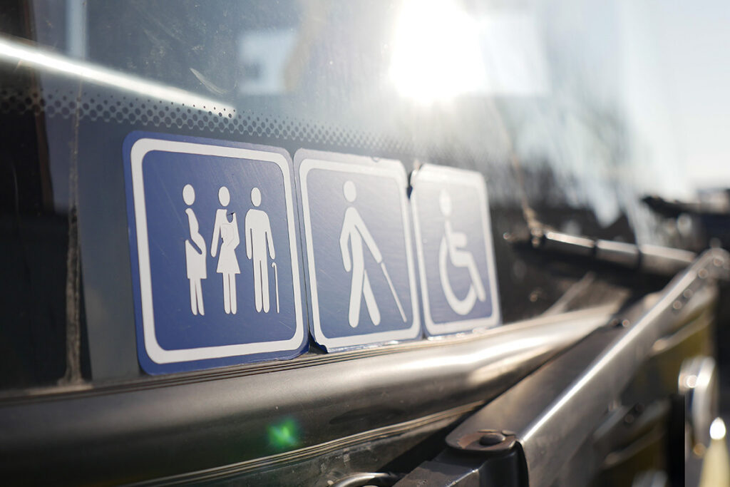 Accessibility sticker icons on the front window of a bus.