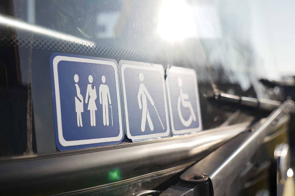 Accessibility sticker icons on the front window of a bus.