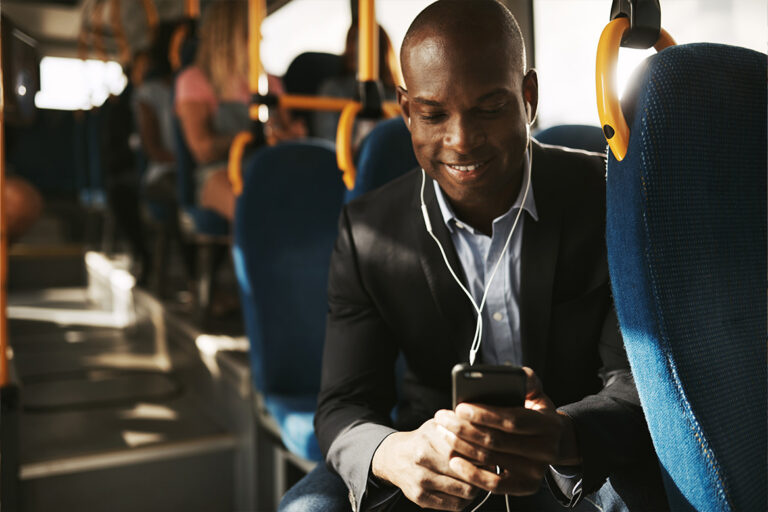 bus patron riding happily while looking at cell phone.