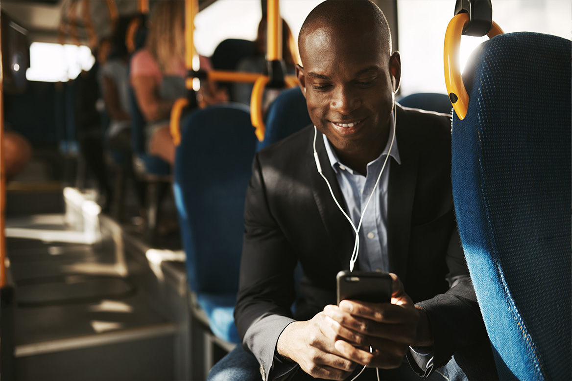 bus patron riding happily while looking at cell phone.