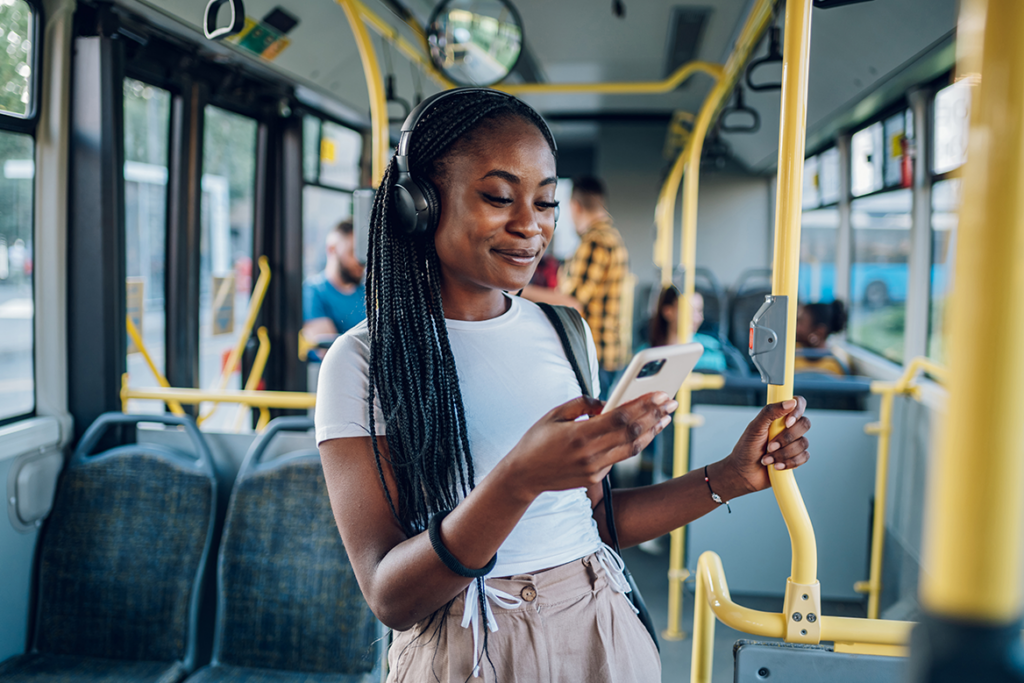 Bus patron checking her cell phone while smiling and riding the bus.