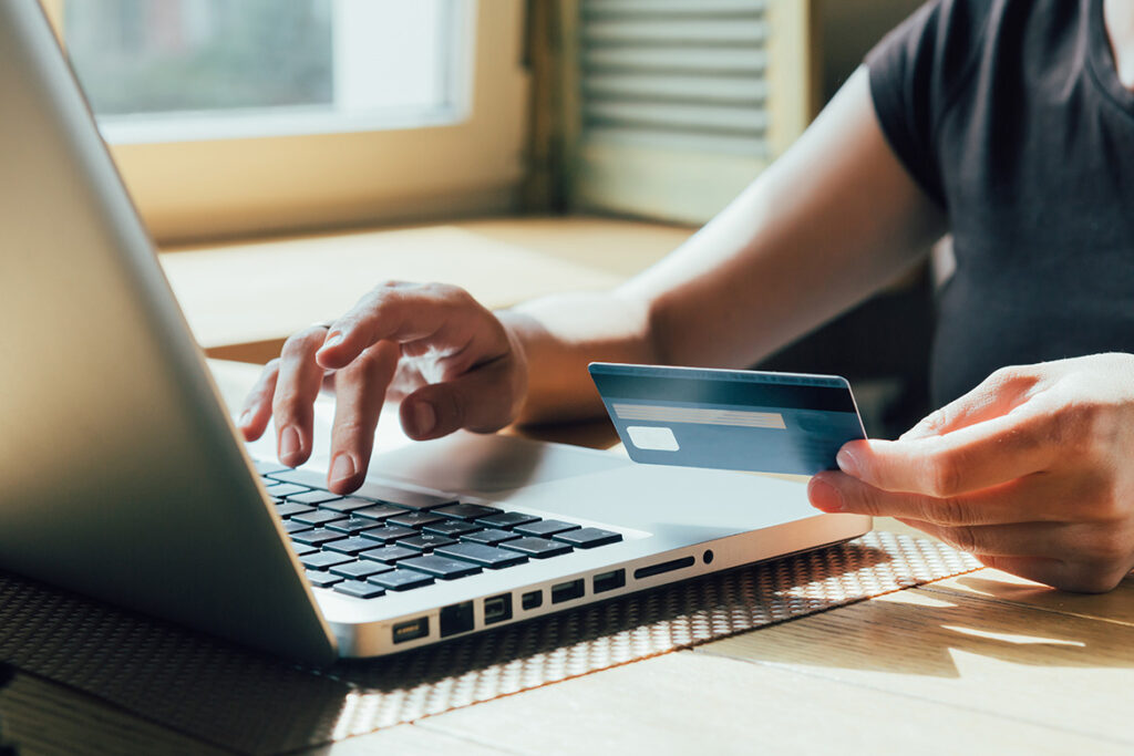 A patron using a laptop and credit card to buy a pass online.