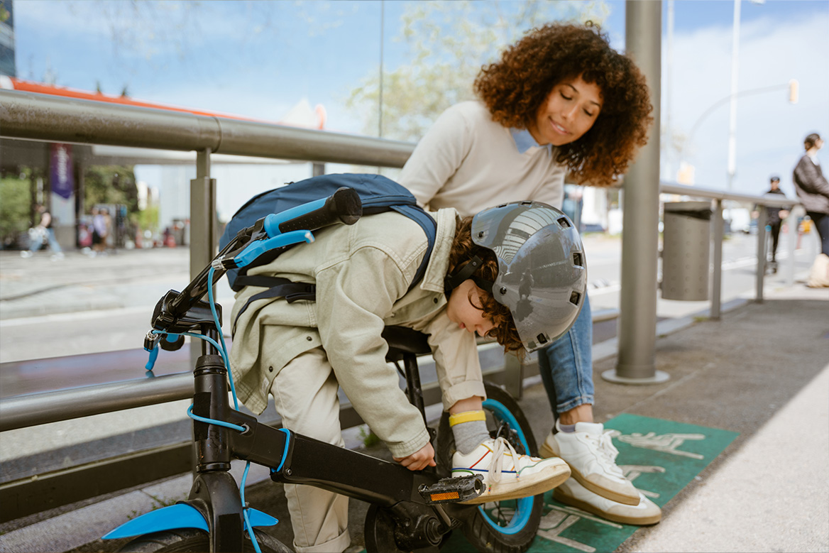 A youngster inspecting his bike at a bus stop.