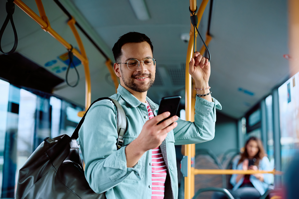 Man receiving a rider alert on his cell phone while aboard a bus.