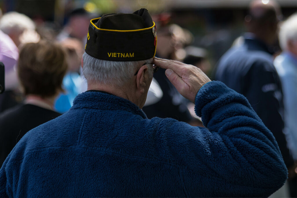 A Vietnam Veteran standing and saluting at a ceremony.